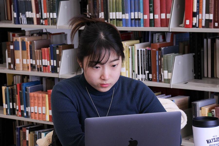 Young woman in the library on a laptop.